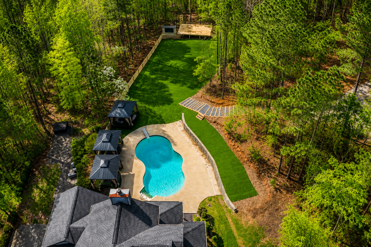 Aerial view of Oasis Cove ATL pool, turf, gazebos, and wooded event area